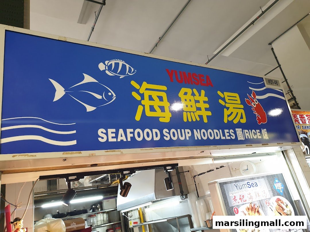 The vibrant blue sign for YumSea Seafood Soup Noodles, featuring fish and shrimp graphics.
