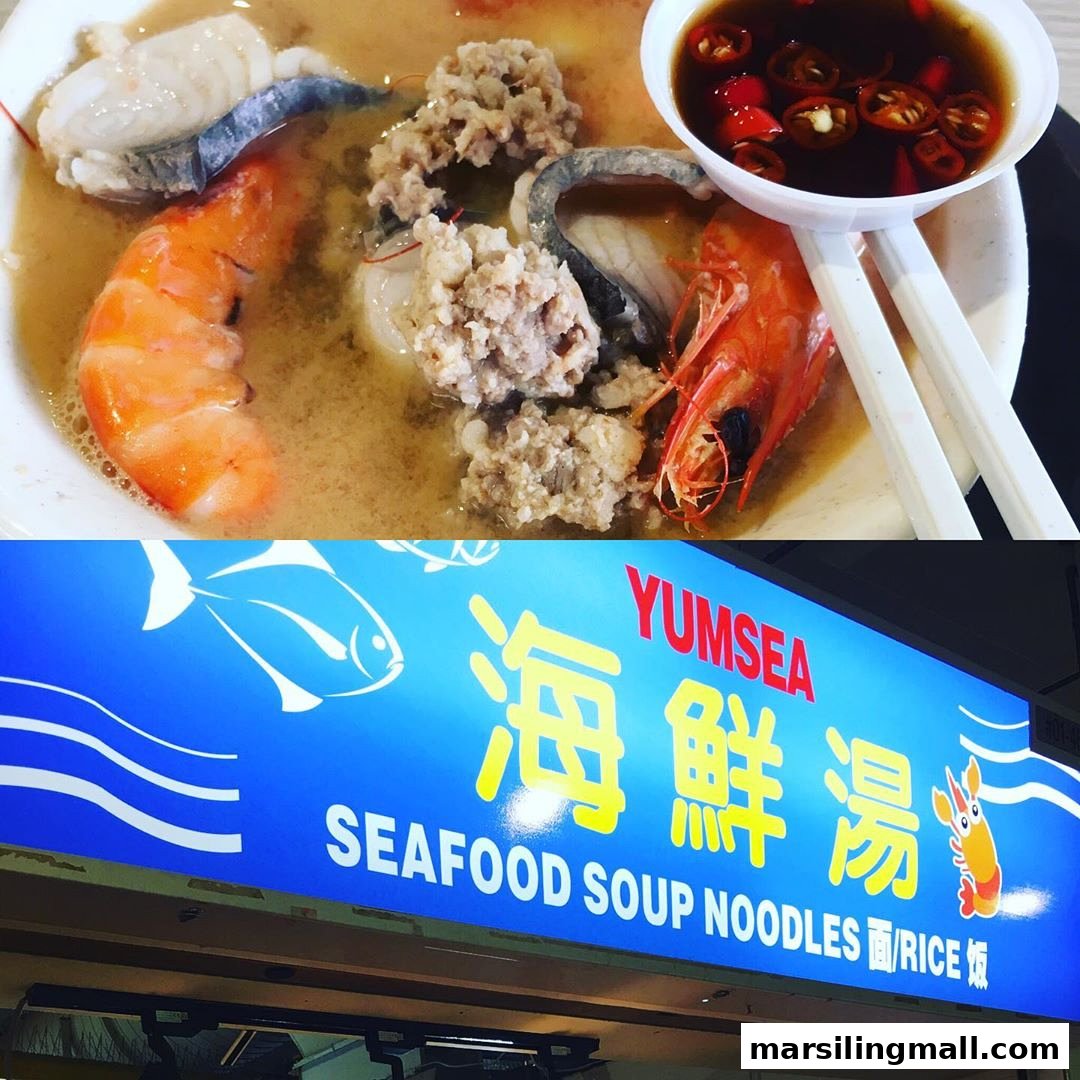 A close-up of a delicious seafood soup with prawns and fish, alongside the YumSea Seafood Soup shop sign.