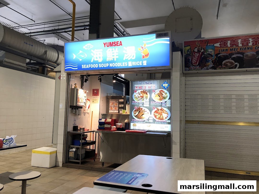 Front view of YumSea Seafood Soup stall with illuminated signage and menu displays.