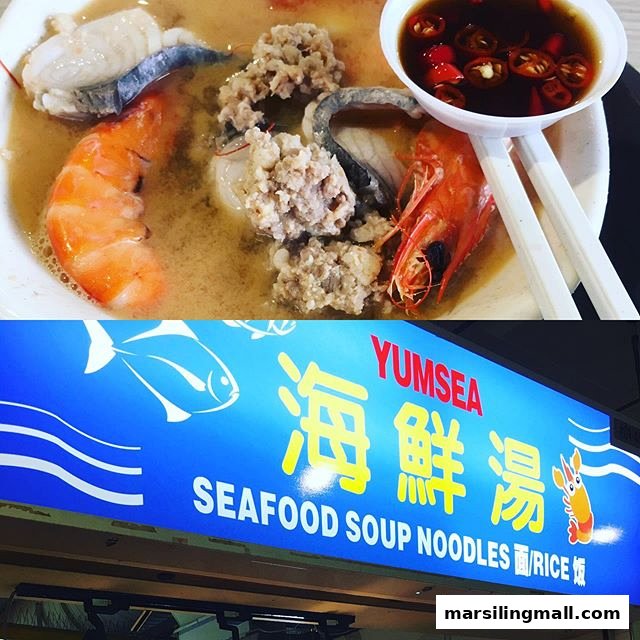 A hearty bowl of seafood soup with prawns, fish, and minced meat, next to the YumSea shop sign.