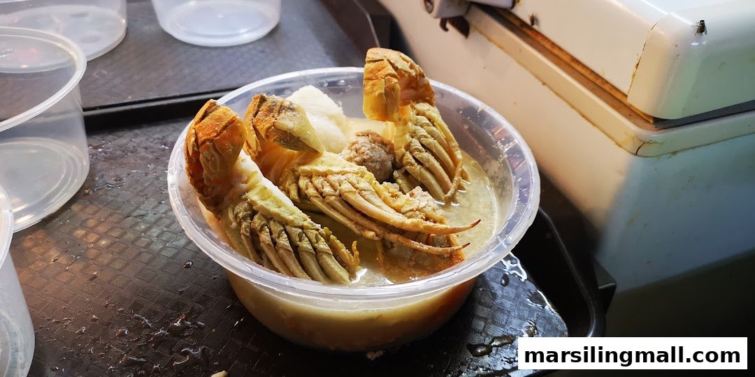 A plastic bowl filled with creamy seafood soup featuring large lobster or crayfish pieces.