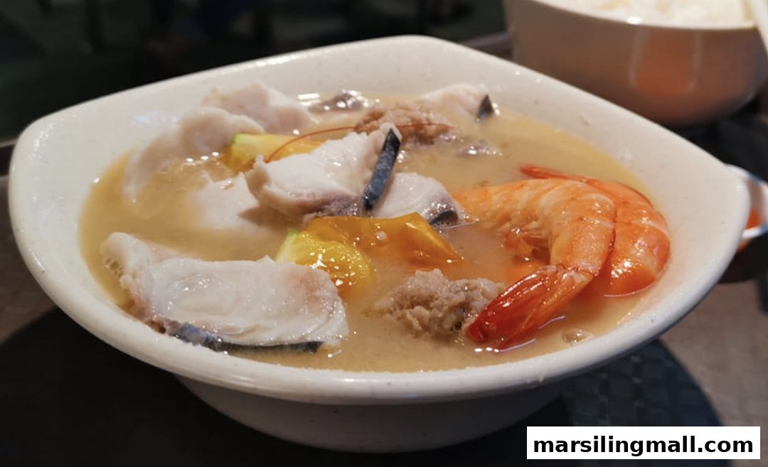 A close-up of a delicious bowl of seafood soup with fish, shrimp, and vegetables.