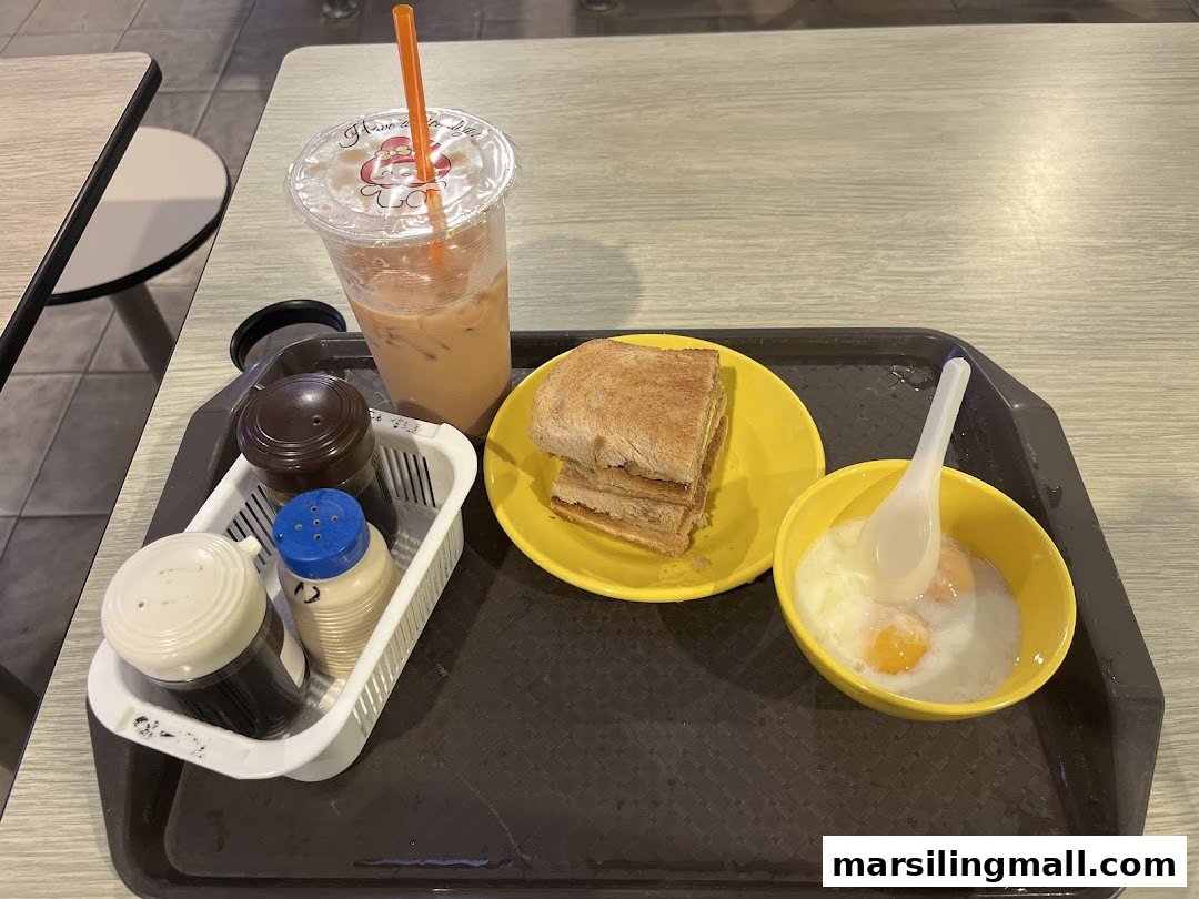 A tray with traditional Singaporean breakfast: kaya toast, soft-boiled eggs, and iced milk tea.