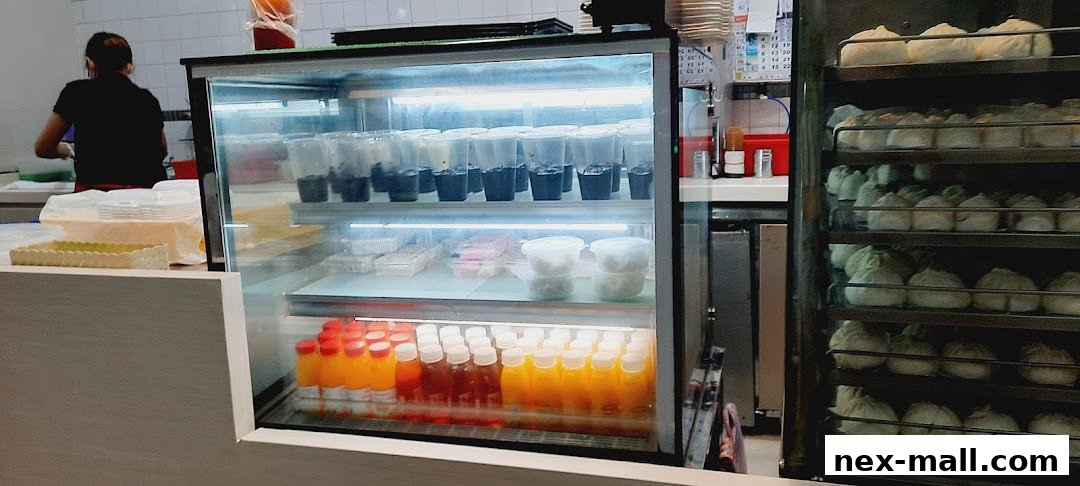 A display case with drinks and food, next to a rack of steamed buns.