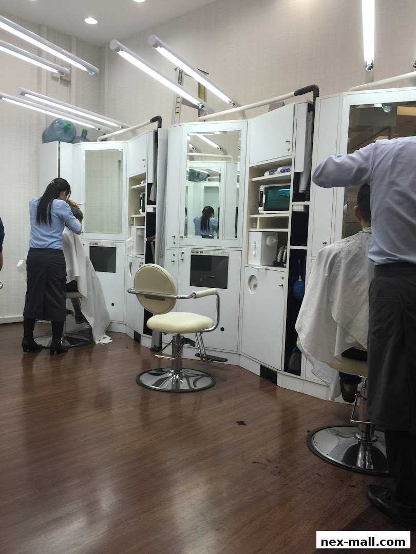 Hairdressers are cutting hair in a modern salon with bright lighting and mirrors.