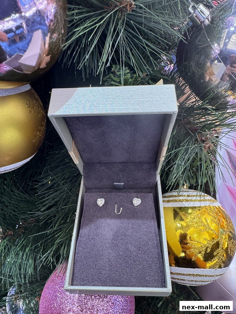A jewelry box with heart-shaped earrings displayed against a festive Christmas tree background.