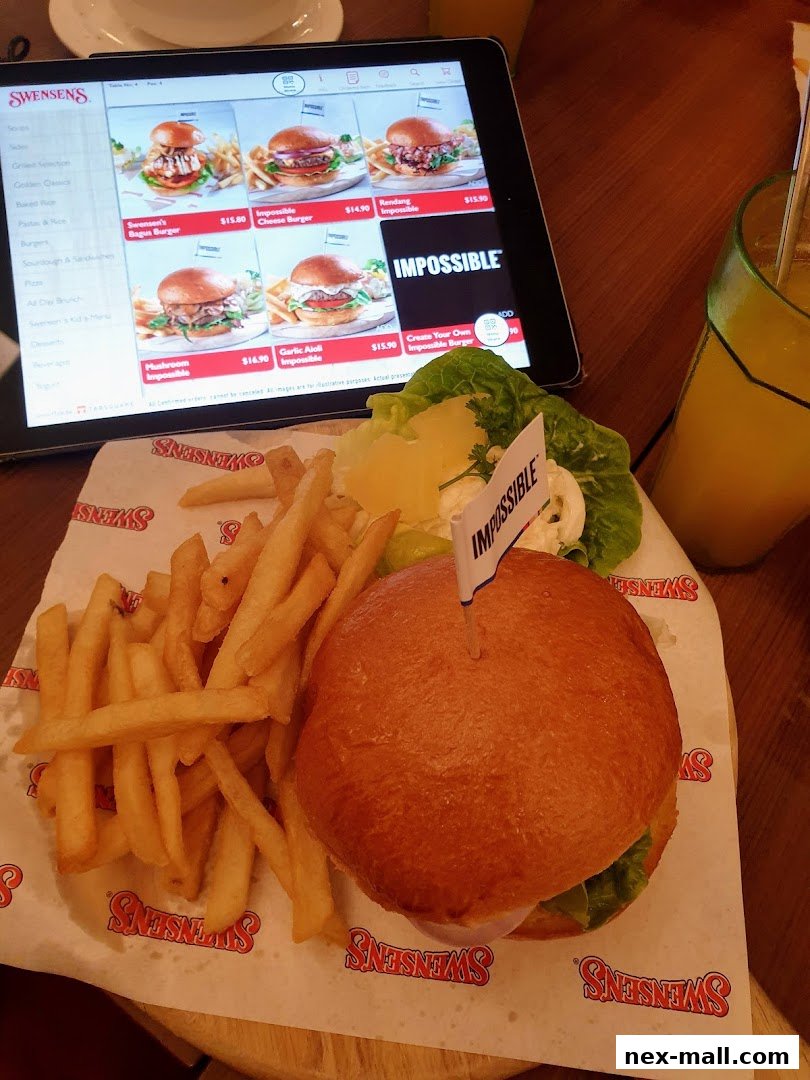 A tablet displays a Swensen's menu with burgers and fries, next to a burger meal.