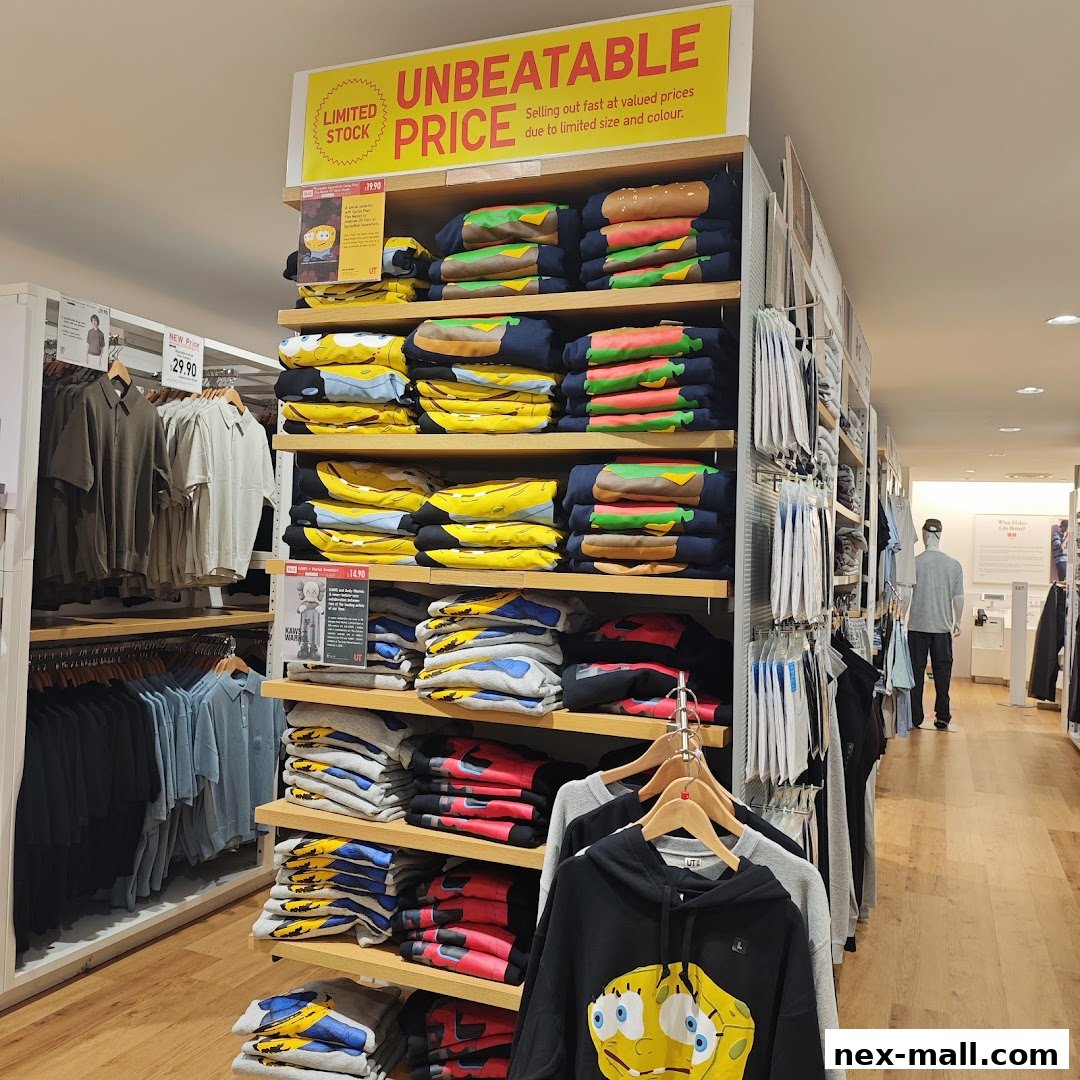 Shelves of folded graphic t-shirts and hoodies, with a sign advertising unbeatable prices.