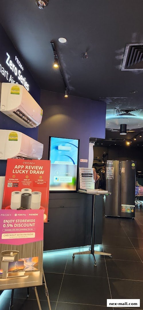 Interior view of a PRISM+ electronics store showcasing air conditioners, refrigerators, and promotional displays.
