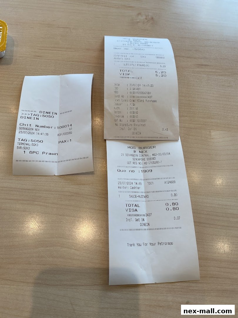 Two MOS Burger receipts are shown on a wooden table, one with a prawn item and the other with sauce.