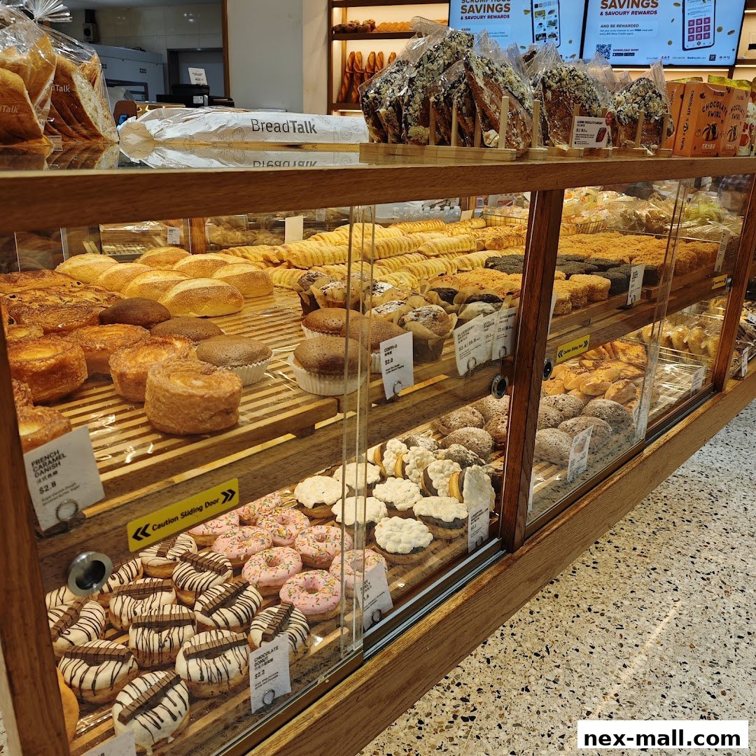 A display case filled with a variety of freshly baked breads, pastries, and donuts at BreadTalk.
