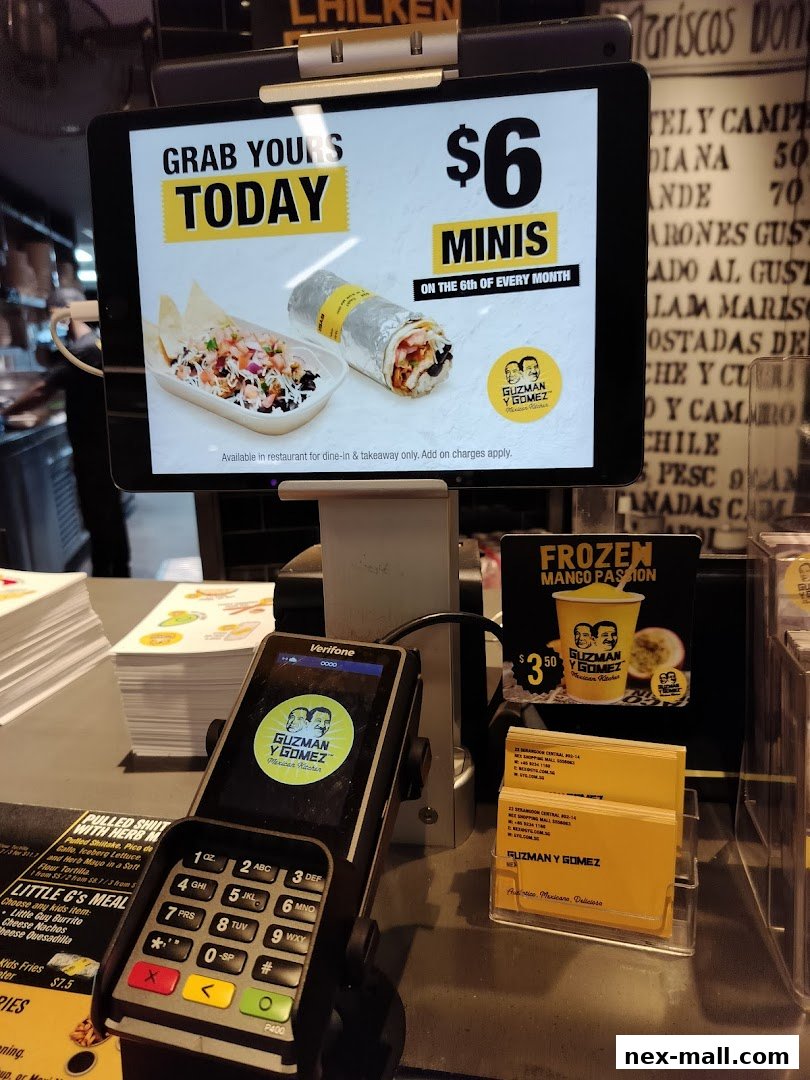 A counter display at Guzman y Gomez featuring a tablet promotion, payment terminal, and business cards.