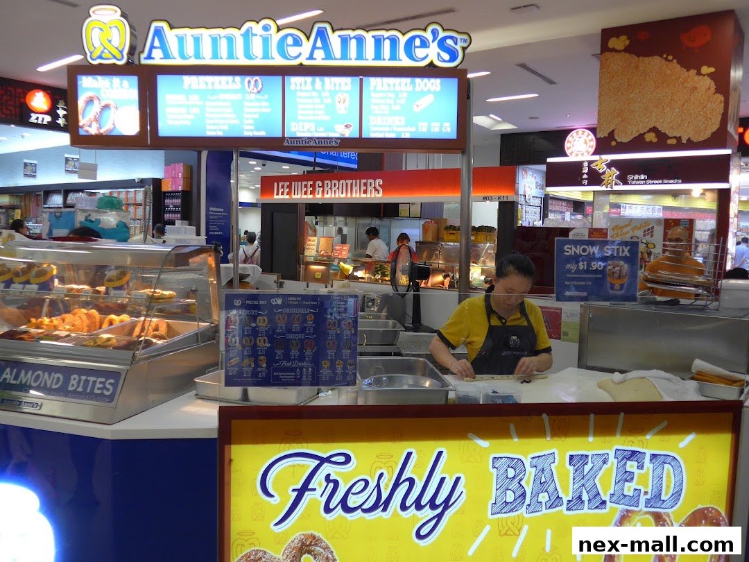 Auntie Anne's pretzel shop with a display of pretzels and a worker preparing dough.