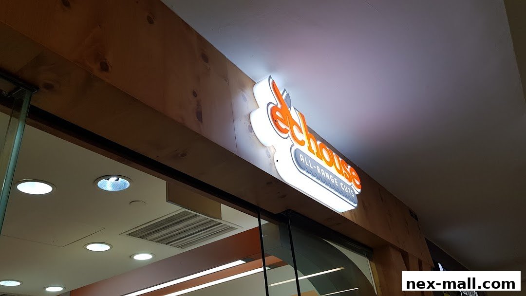 The illuminated sign for EC House All Range Cuts is mounted on a wooden facade above a shop entrance.