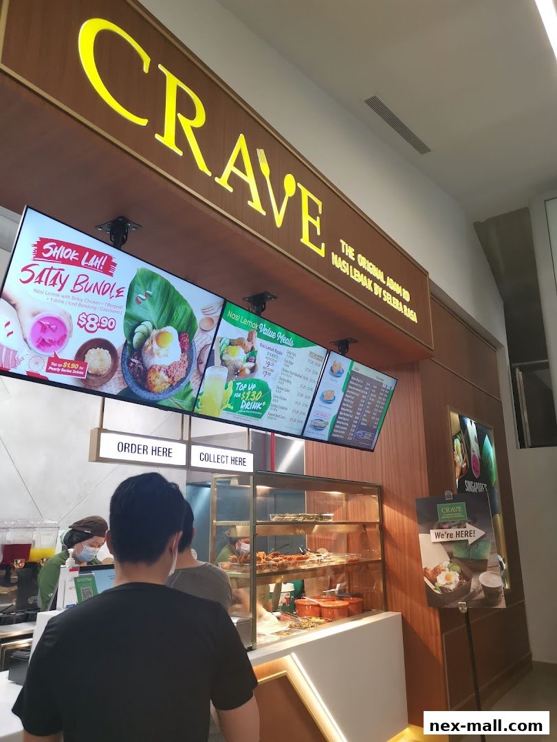 The entrance of Crave Nasi Lemak, showcasing menu boards and a display of food.