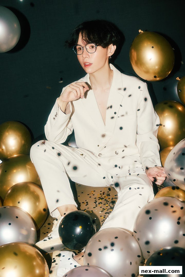A person in a white suit sits surrounded by balloons and confetti.