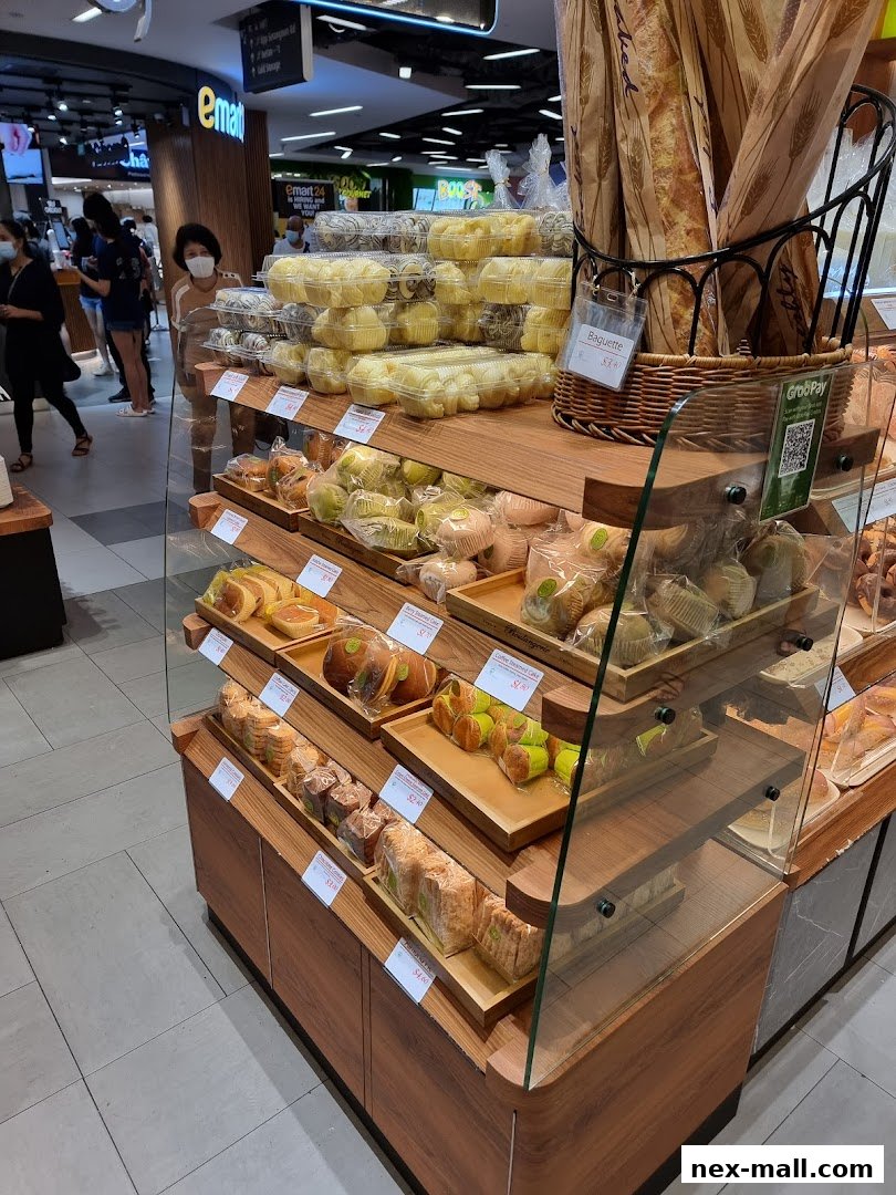A display of various baked goods, including baguettes, cakes, and bread, at a bakery.