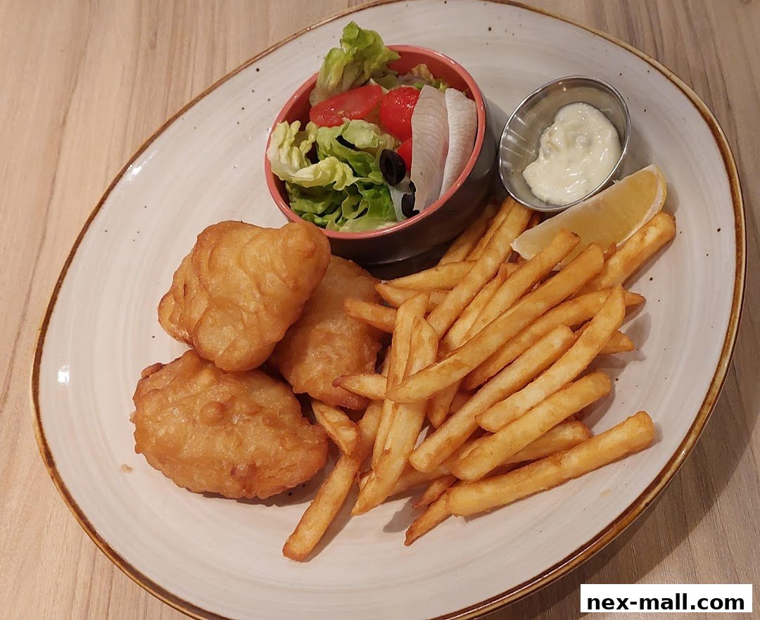 A plate of fish and chips with a side salad and tartar sauce.