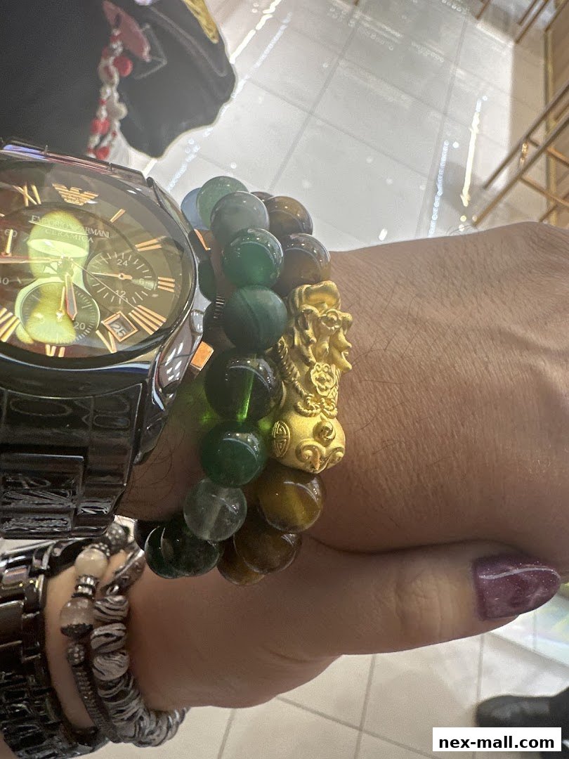 A close-up of a wrist adorned with multiple bracelets and a luxury watch.