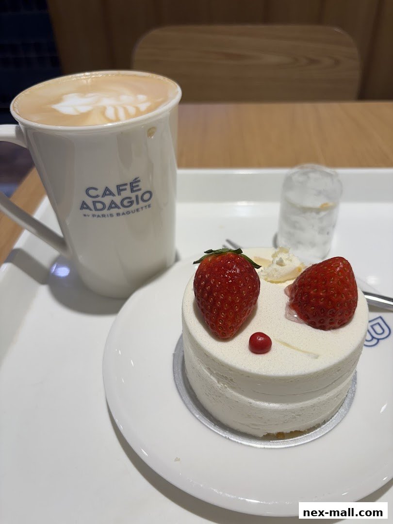 A white cake topped with strawberries and a latte with latte art.