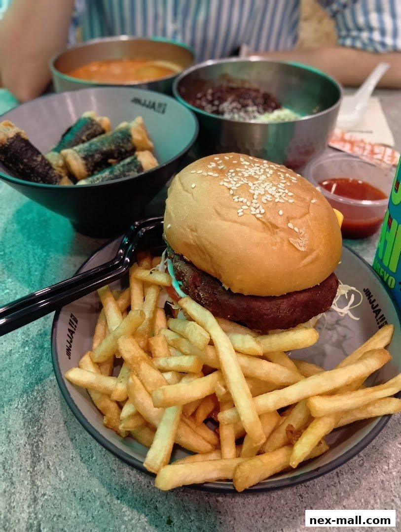 A close-up of a Korean fried chicken meal with a burger, fries, and seaweed rolls.