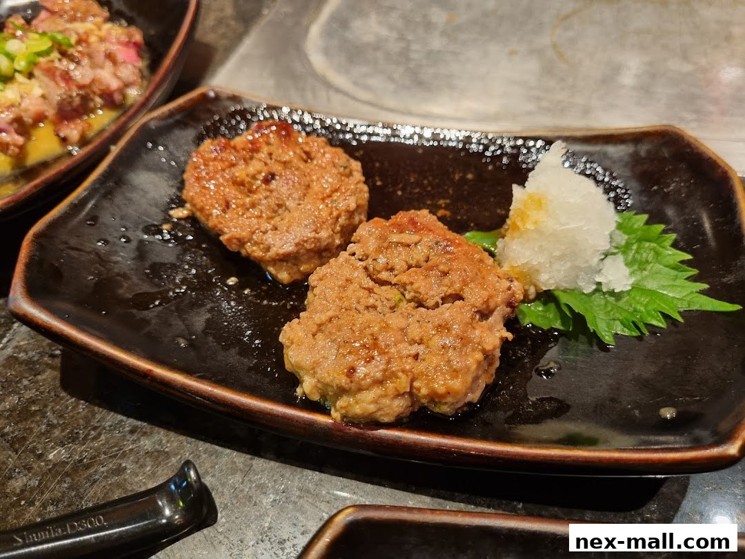 Two grilled patties served with grated radish and a green leaf on a black plate.