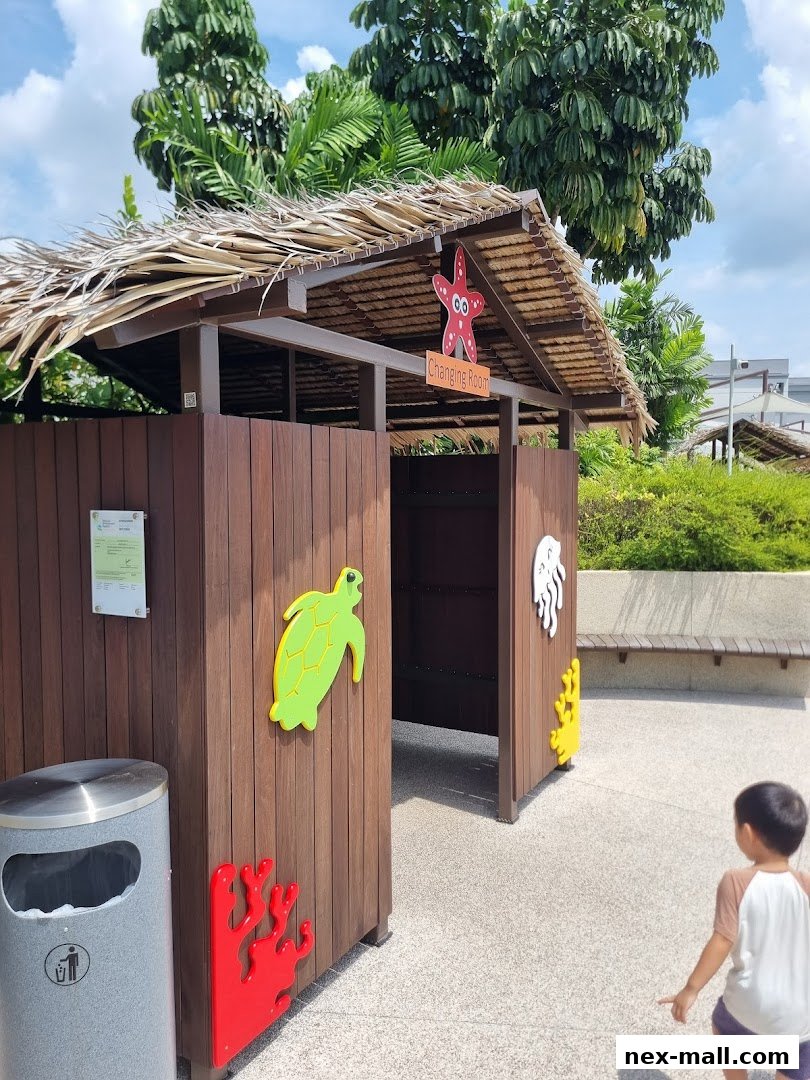 A child approaches a wooden changing room with marine-themed decorations and a thatched roof.