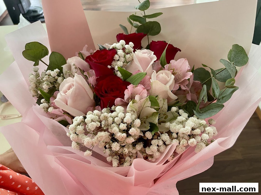 A beautiful bouquet of red and pink roses with baby's breath and eucalyptus, wrapped in pink paper.