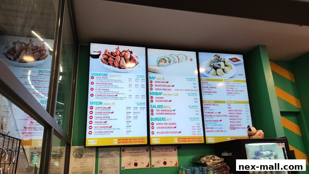A digital menu board displaying various Korean dishes including chicken, noodles, kimbap, salads, and burgers.
