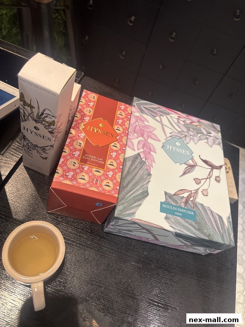 Three boxes of HYSSES diffusers and a cup of tea on a dark surface.