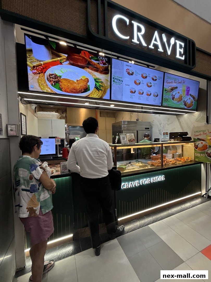Customers ordering at a Crave Nasi Lemak food stall with digital menus displaying food items.