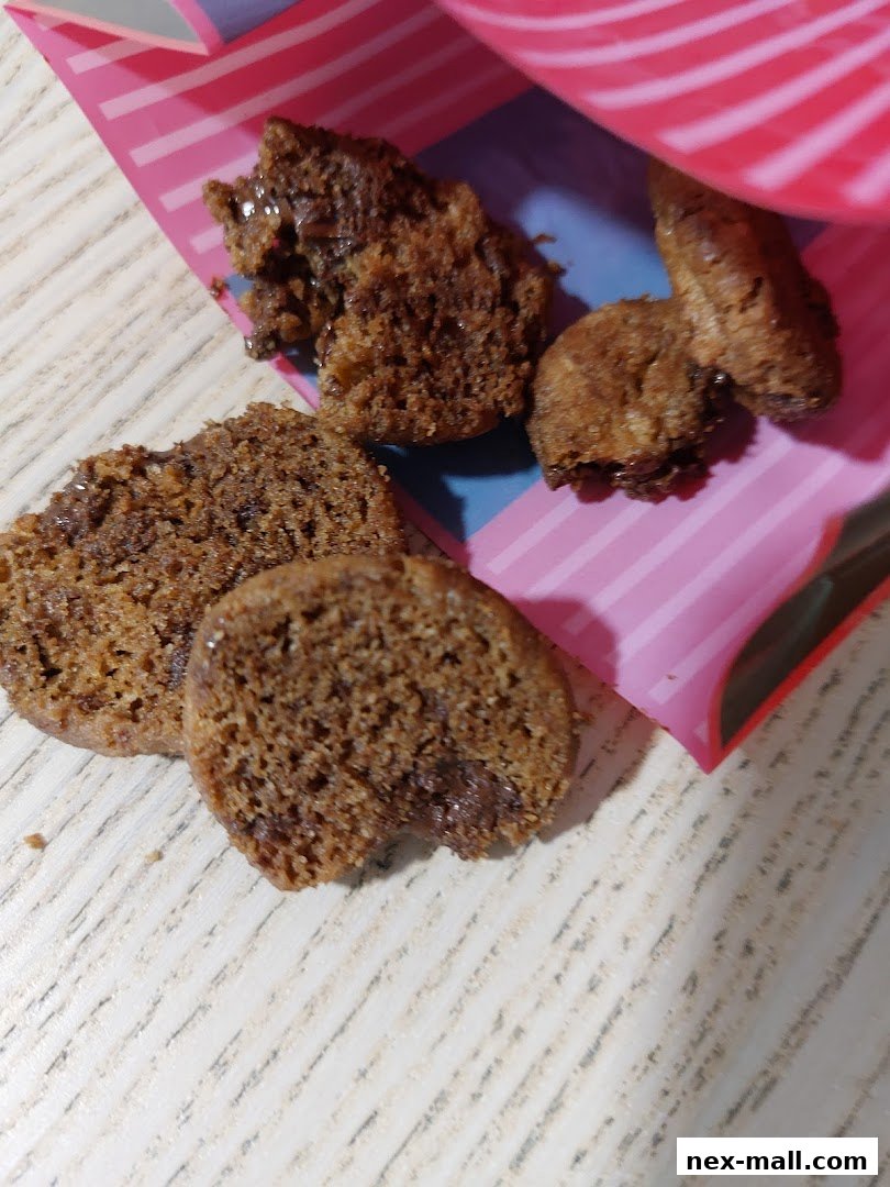 Close-up of broken chocolate chip cookies spilling out of a pink and white striped bag.