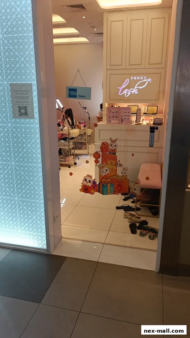 Entrance to Perky Lash, an eyelash extension salon, with a staff member working inside.