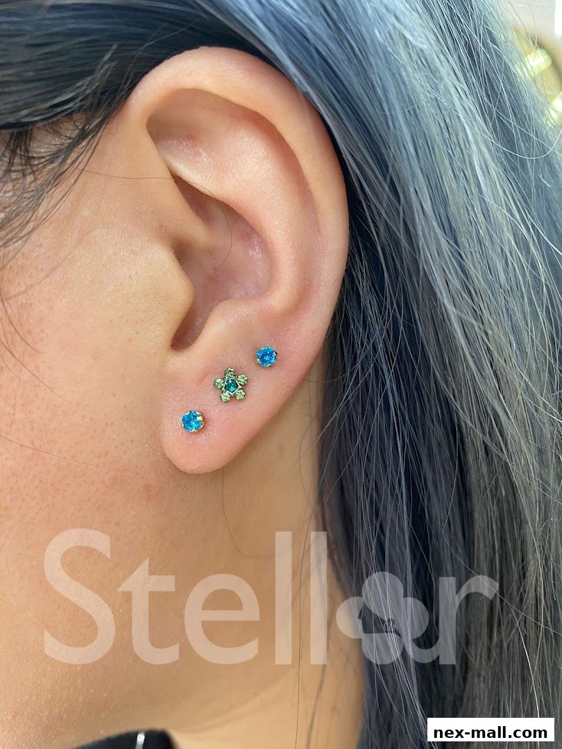 Close-up of a person's ear showcasing three stylish ear piercings with sparkling jewelry.
