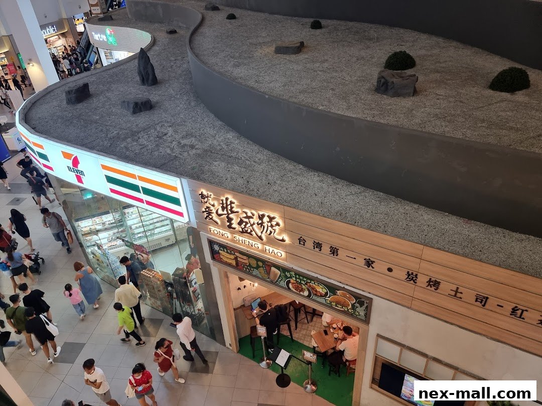 A 7-Eleven store and a food establishment with outdoor seating in a mall.