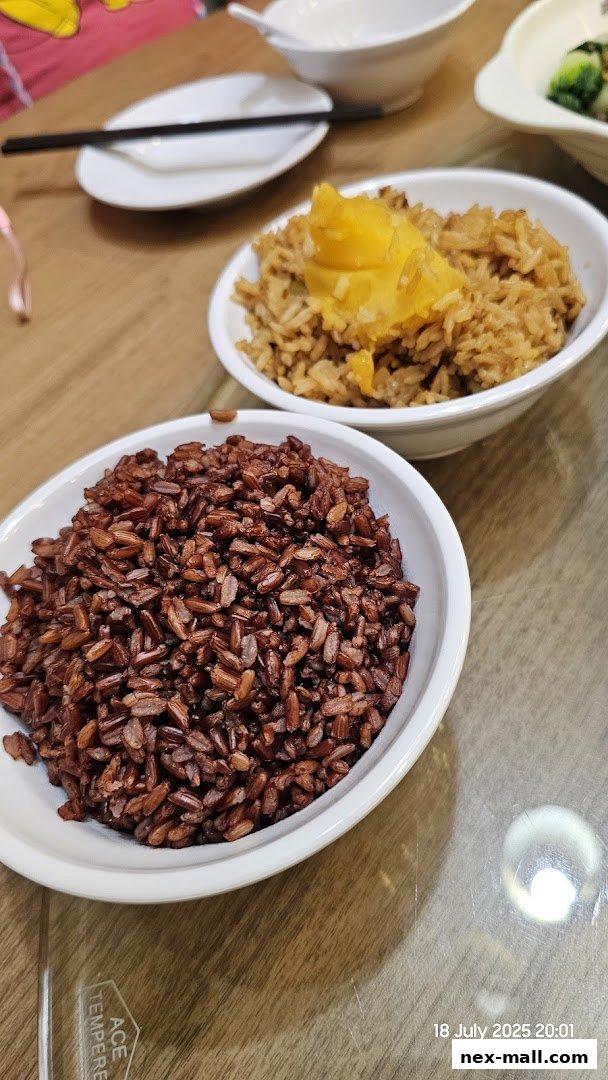 Two bowls of rice, one brown and one with toppings, are served on a wooden table.