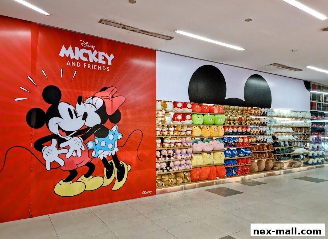 A MINISO NEX store interior featuring a large Mickey and Friends mural and shelves stocked with plush toys.