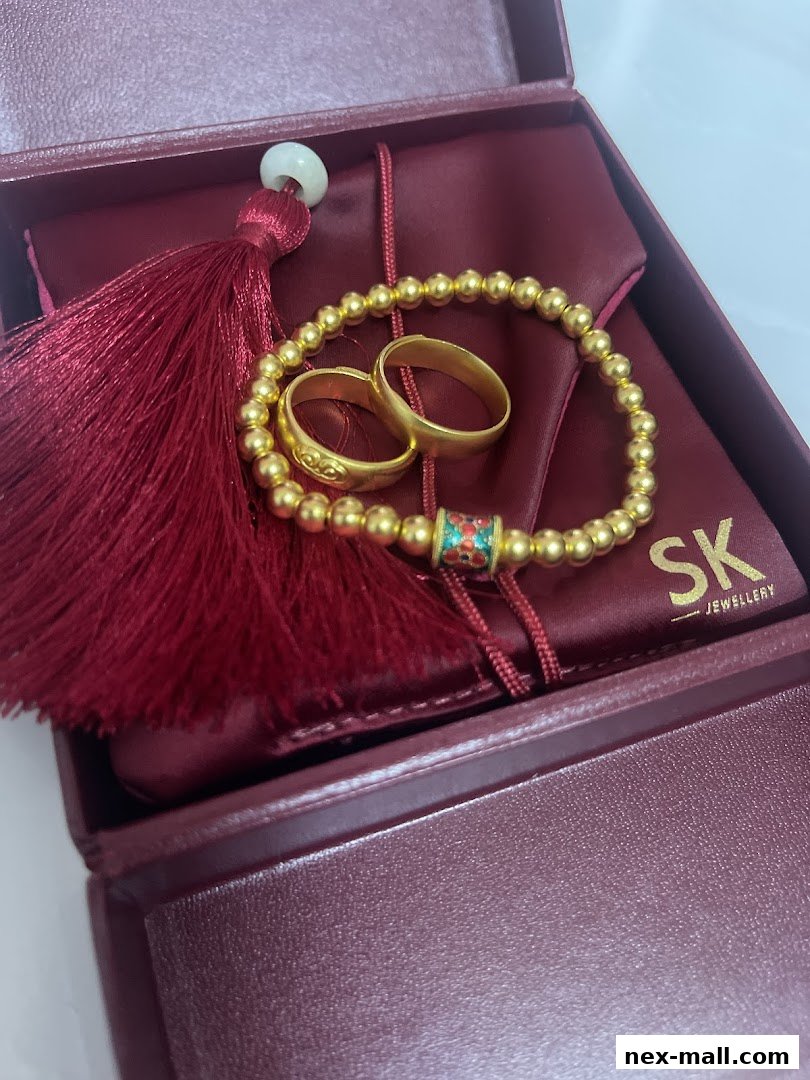 A close-up of gold rings and a beaded bracelet with a tassel in a jewelry box.