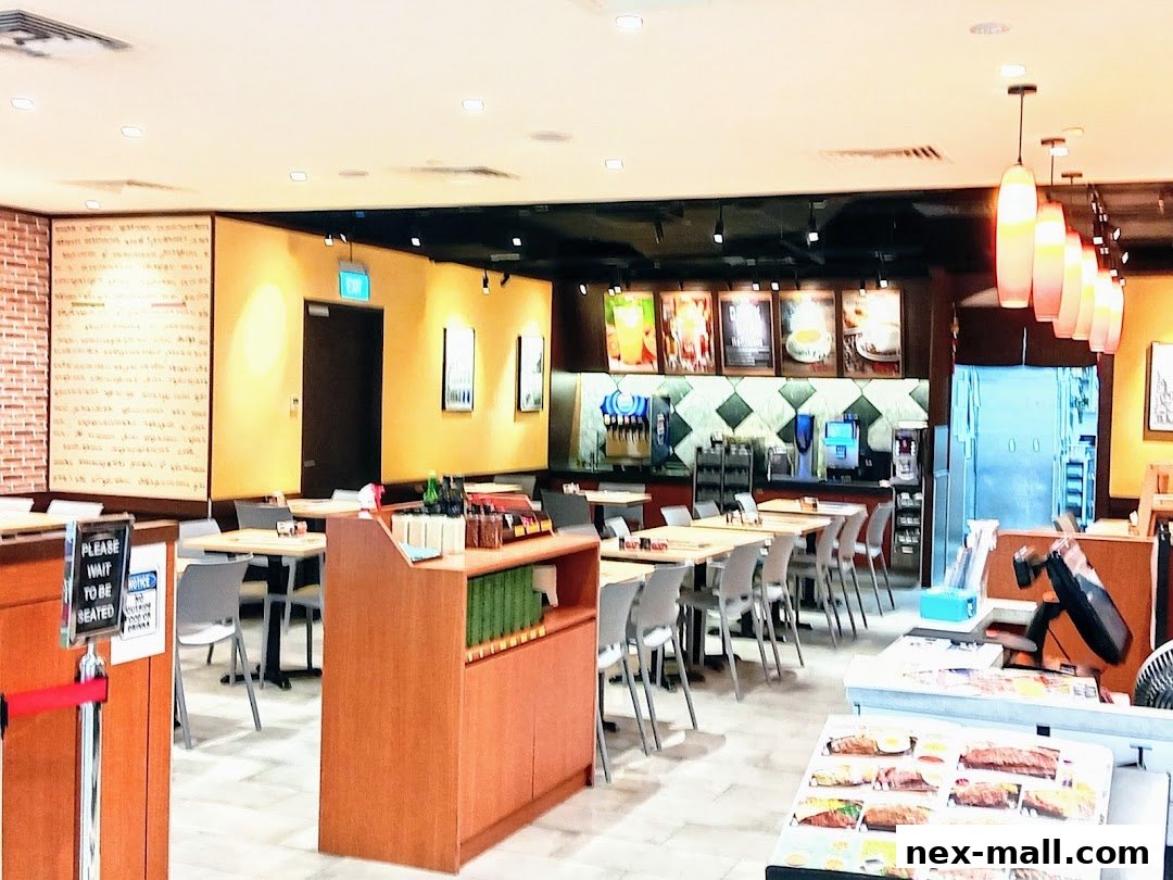 Interior view of a Saizeriya restaurant with tables, chairs, and a service counter.