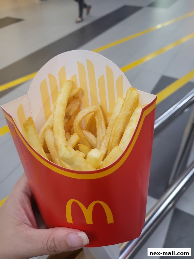 A hand holds a red carton of McDonald's french fries.
