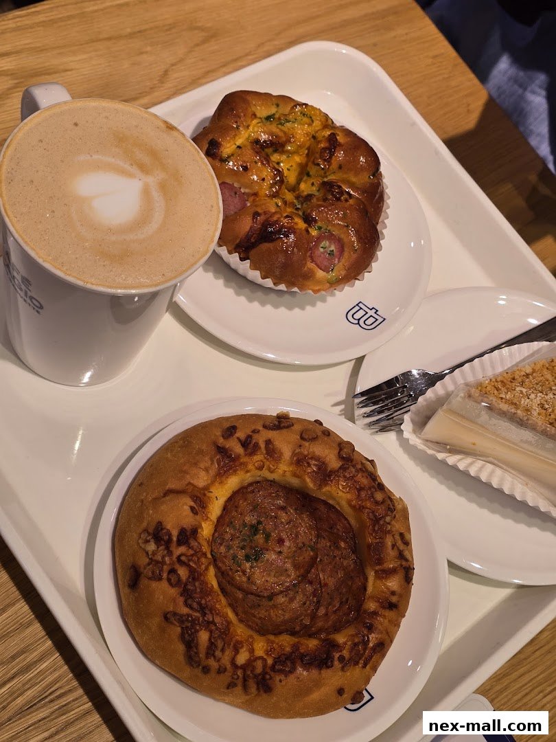 A tray with a latte, two savory pastries, and a slice of cake.