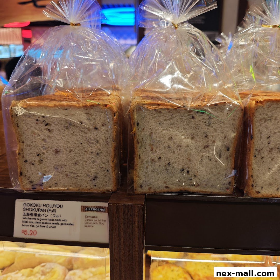 Loaves of Japanese bread with black sesame seeds are displayed in clear plastic bags.