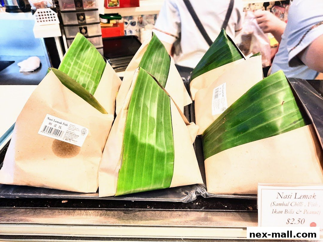 Wrapped Nasi Lemak dishes with banana leaves and paper packaging, displayed for sale.