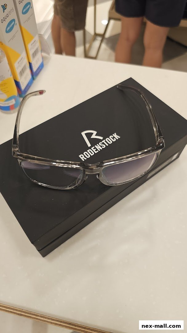 A pair of Rodenstock eyeglasses displayed on a black box with lens cleaner bottles in the background.