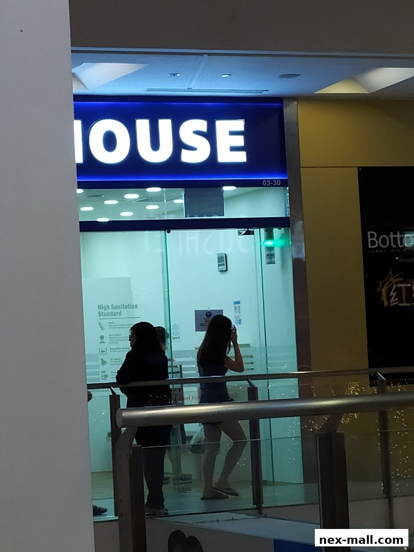 The entrance of QB HOUSE NEX with a bright blue sign and people inside.