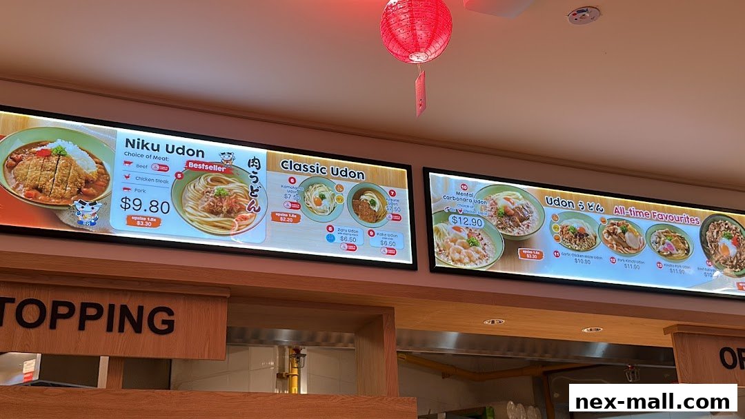 A digital menu board displaying various udon dishes with prices and images.