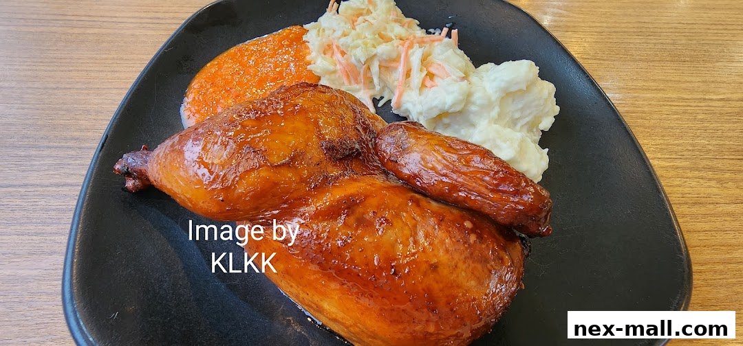 A close-up of a glossy, roasted chicken quarter with mashed potatoes and coleslaw.