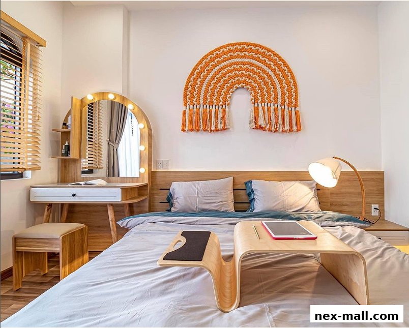 A bedroom with a vanity, bed, and a macrame rainbow wall hanging.