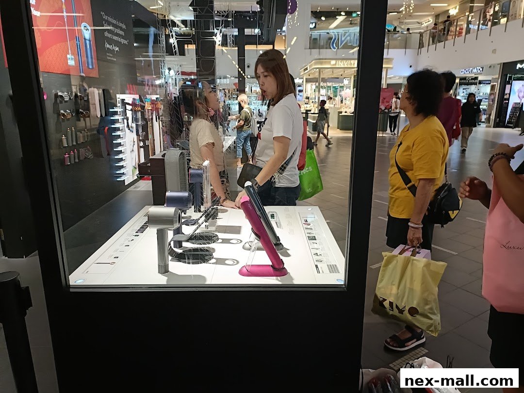 People looking at Dyson products displayed in a shop window at a mall.