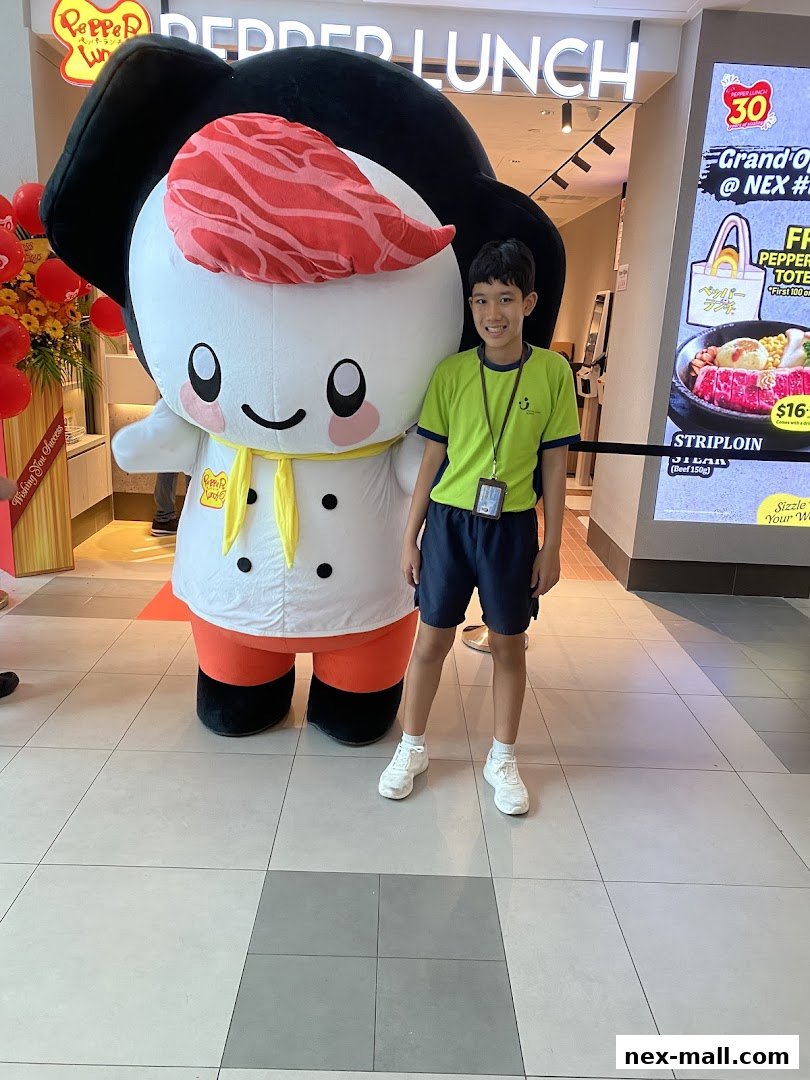 A boy poses with a Pepper Lunch mascot in front of the restaurant.